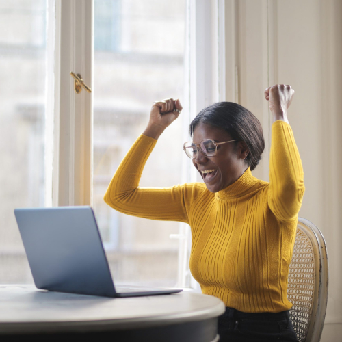 black woman rejoices in front of a computer